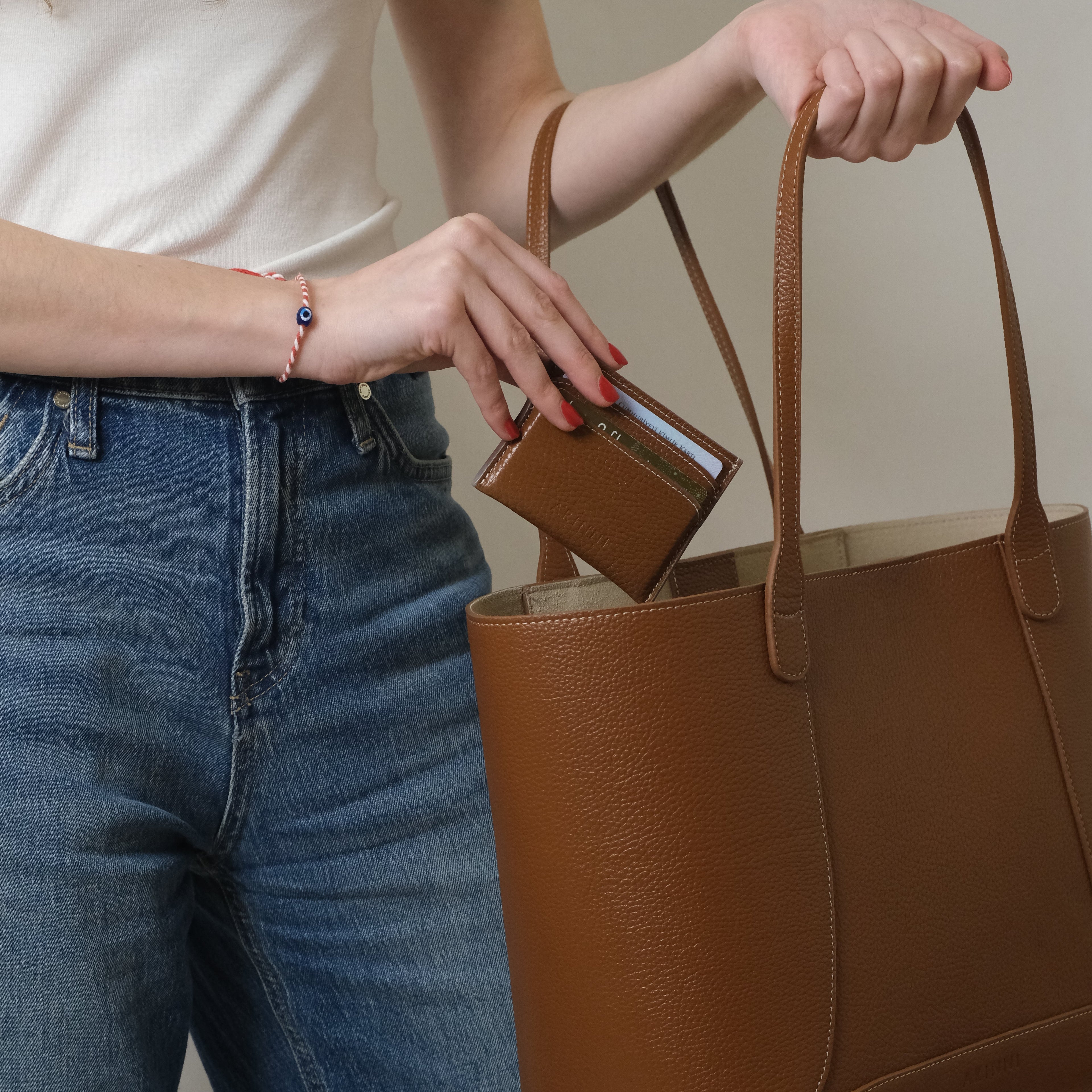 Person reaching into a brown leather bag to take out a wallet.