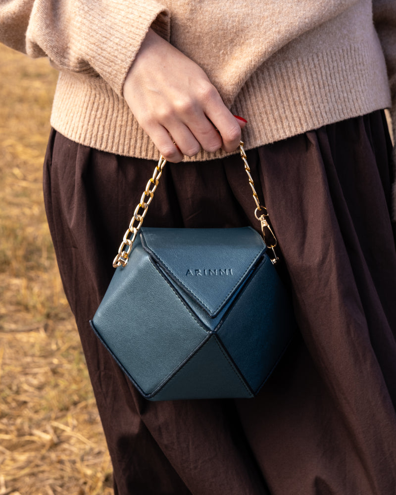 Person holding a green geometric handbag with a natural background